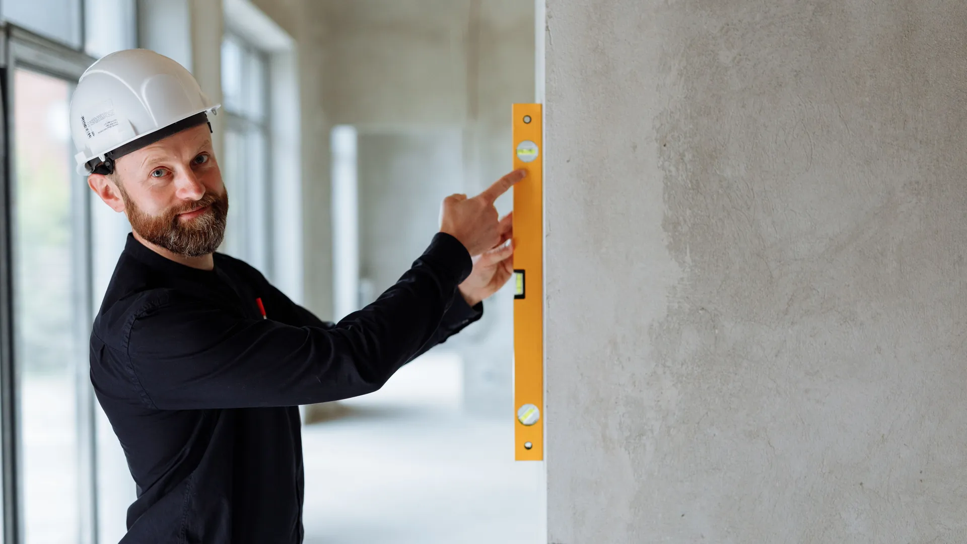 Worker in a hard hat checking an interior wall with a level